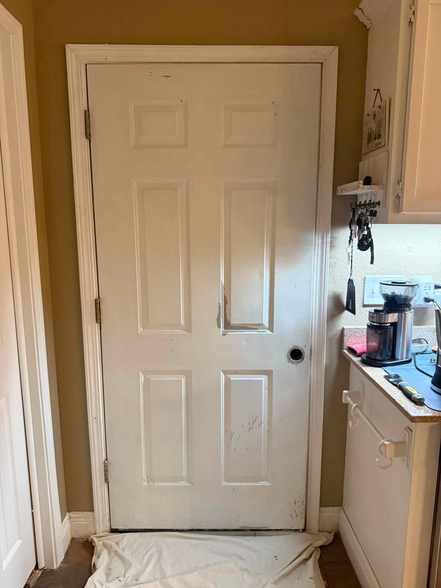 Kitchen pantry door and trim being painted white, with a drop cloth protecting the floor